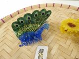 a small glass peacock sitting on a table next to a yellow flower