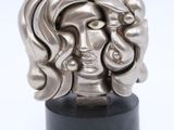 a close up of a sculpture of a woman ' s face on a black stand