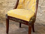 a chair with a yellow upholstered seat in front of a brick wall