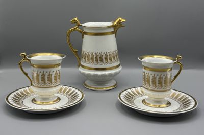 trois tasses à café blanches et dorées avec leurs soucoupes, posées sur une table