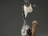 sculpture en bronze représentant une femme tenant un sac posé sur un morceau de bois