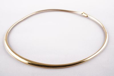 gros plan d'un collier en or sur une surface blanche