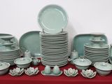 many plates and bowls on a table with a red table cloth