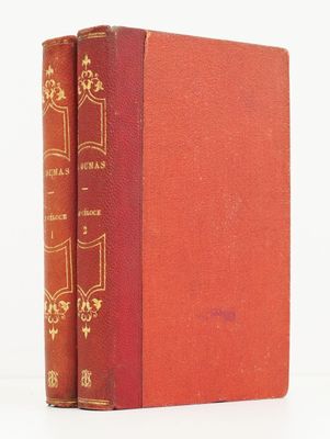un vieux livre posé sur une table blanche à côté d'un livre rouge