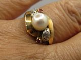 a close up of a person ' s hand wearing a ring with a pearl on it