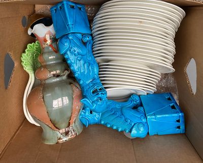 a cardboard box with a bunch of plates and vases in it
