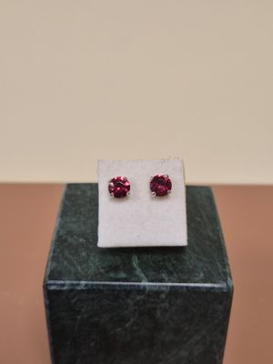 a pair of pink sapphire stud earrings sitting on top of a marble block