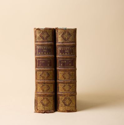 deux vieux livres posés l'un sur l'autre sur une surface blanche