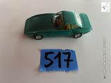une petite voiture verte posée à côté d'une feuille de papier bleue