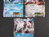 Trois cartes Pokémon sont posées sur une table avec un fond noir.
