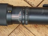 un gros plan sur l'objectif d'un appareil photo posé sur un parquet