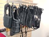 de nombreux gilets de sauvetage suspendus à un porte-gilets dans une pièce