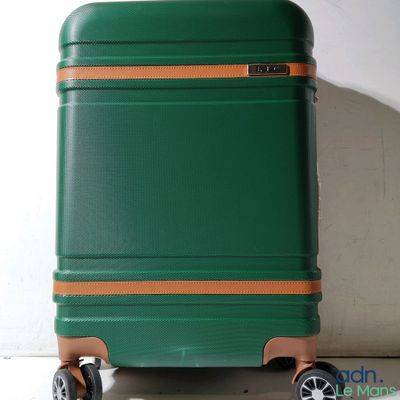 a green suitcase sitting on wheels against a white wall