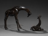 two bronze statues of giraffes and a giraffe laying on the ground
