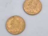 two gold coins sitting next to each other on a white surface