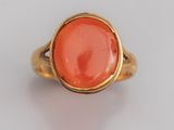 une bague en or ornée d'une pierre de corail ovale au centre