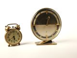 deux horloges placées l'une à côté de l'autre sur une surface blanche