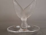 a glass bird that is sitting on top of a glass plate