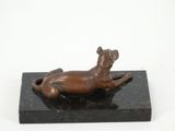 bronze sculpture of a dog laying on a black marble base