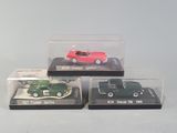 three miniature cars in a display case on a table