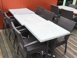 des tables et des chaises sur une terrasse en bois, avec un mur rouge en arrière-plan