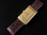 a gold watch on a black surface with a black background