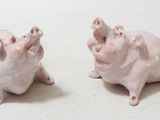 two pig figurines sitting next to each other on a table