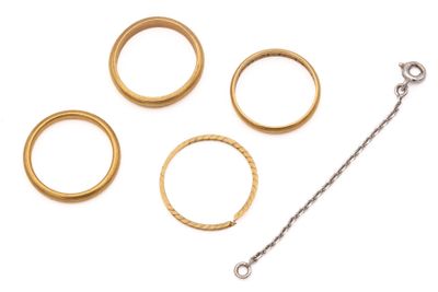 four gold rings and a chain on a white surface