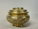 a gold vase with a lid on a white surface