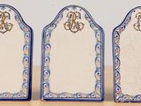 three blue and white plates with monograms on them sitting on a table