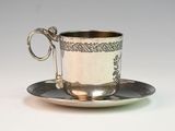 a silver cup and saucer on a saucer
