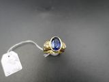 a close up of a ring with a blue stone on a black surface