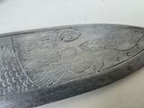 a close up of a knife with a carving of a fish on it