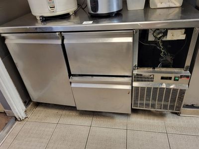 une petite cuisine équipée d'appareils électroménagers en inox, disposés sur le plan de travail