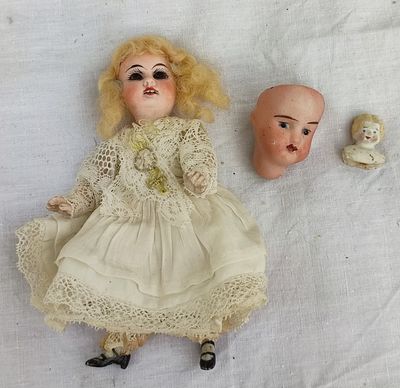 une poupée et une tête de poupée posées sur un drap blanc