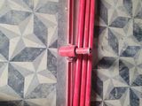 un radiateur rouge posé sur un sol carrelé, à côté d'un tuyau rouge