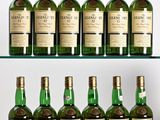 several bottles of whisky are lined up on a glass shelf