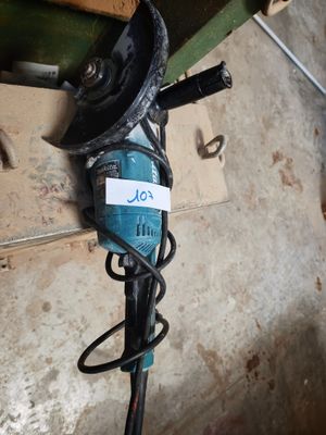 a blue and black drill on the floor next to a wall