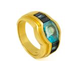 gros plan d'une bague en or avec une pierre bleue