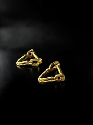 a pair of gold earrings on a black background