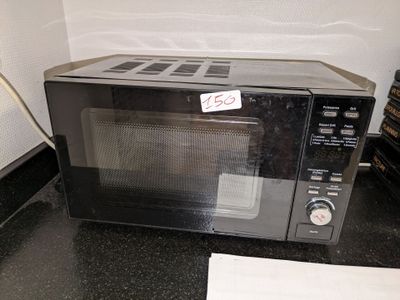 un micro-ondes noir posé sur le plan de travail d'une cuisine