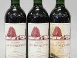 trois bouteilles de vin rouge sont alignées sur une surface blanche