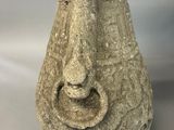 a stone vase with a face on it on a table