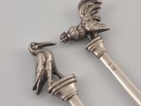 pair of silver spoons with a bird on top of them