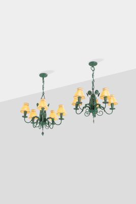 two green chandeliers with yellow lamps hanging from the ceiling
