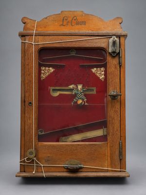 une vieille horloge en bois avec un couvercle rouge et une clé sur le devant