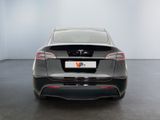 the rear end of a grey car in a white room