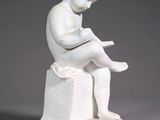 a white statue of a boy reading a book