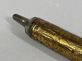 an image of a gold colored pen sitting on top of a white surface