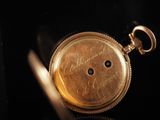 a close up of a gold pocket watch on a black surface